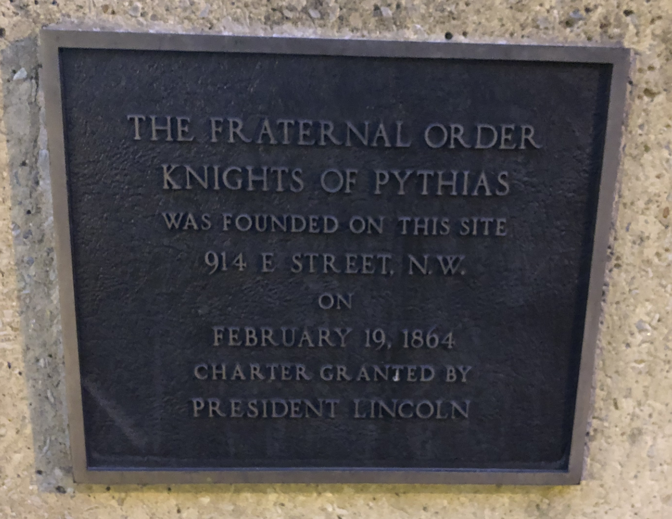 Photo of plaque with inscription reading "The Fraternal Order Knights of Pythias Was Founded on This Site. 914 E. Street, N.W. on February 19, 1864. Charter Granted by President Lincoln"