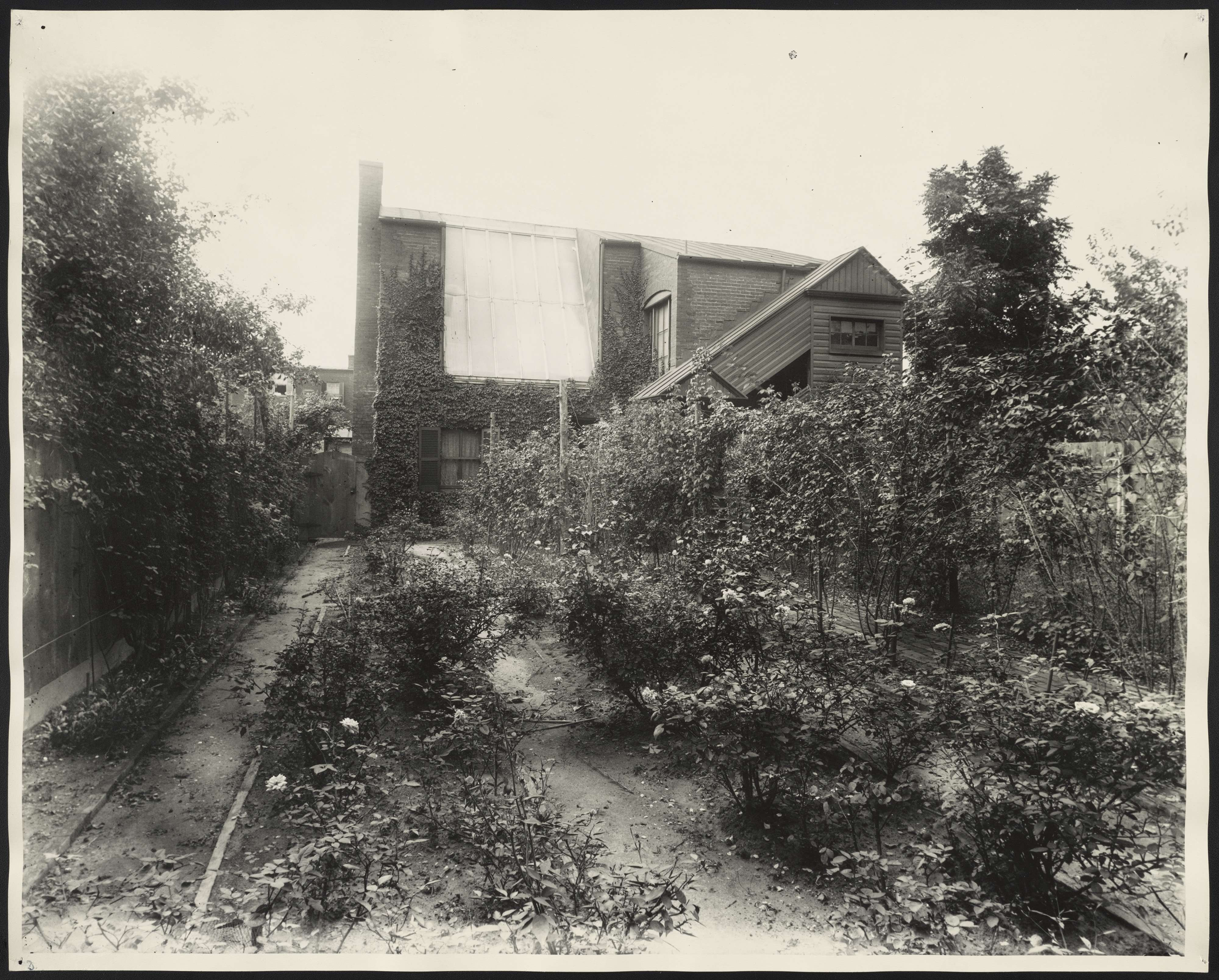 Exterior photo of Frances Benjamin Johnston's home and photo studio in Washington, DC, showing brick building with rose garden. (Source: Library of Congress).