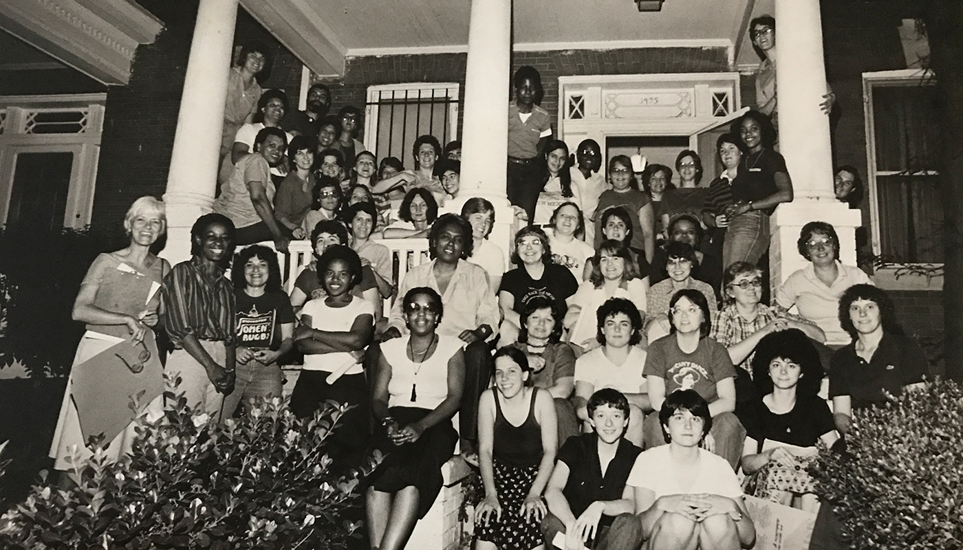 Black and white image of Sisterfire staff and volunteers gathered on a front porch posing.