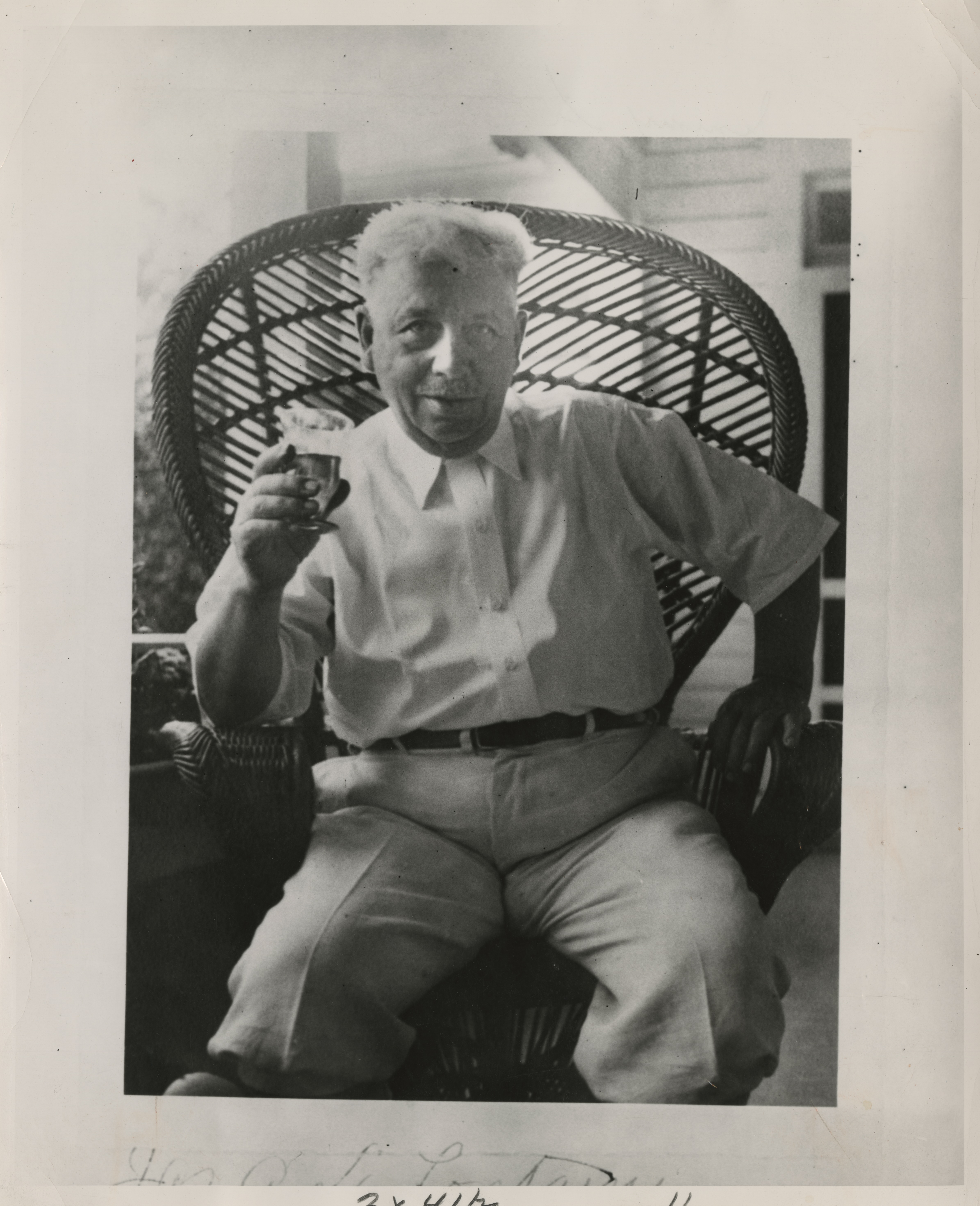 An older man holds up a drink to the camera.