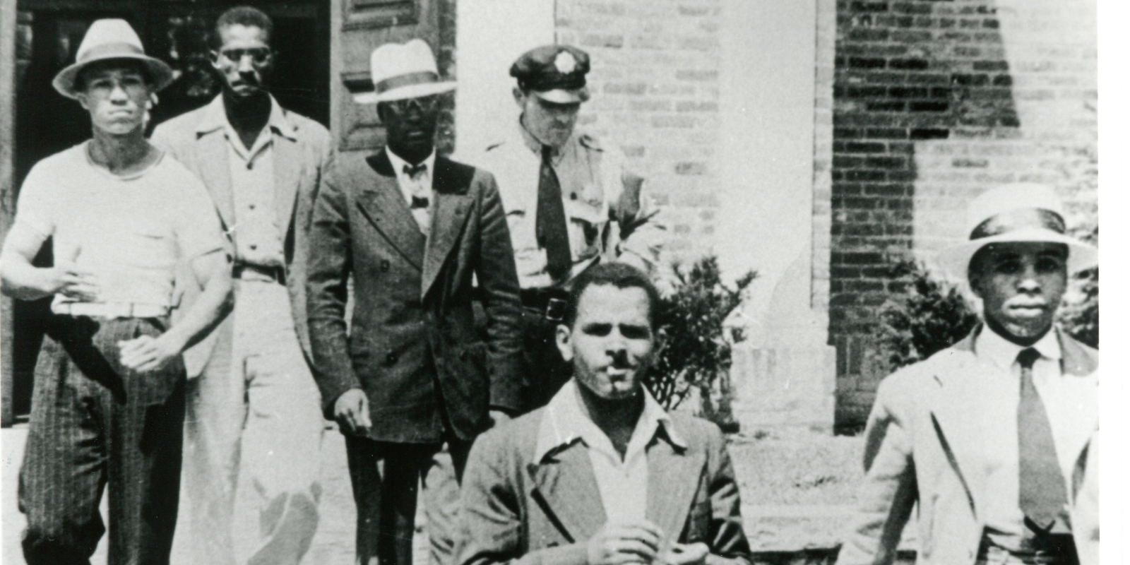 Police officer escorts five young African American men out of the Alexandria, VA Library on August 21, 1939.