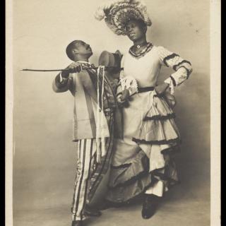 Two black actors, Gregory and Brown, one in drag, dancing the Cake-Walk in Paris. Photographic postcard, 1903