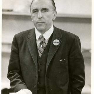 Frank Kameny wears a suit and smiles.