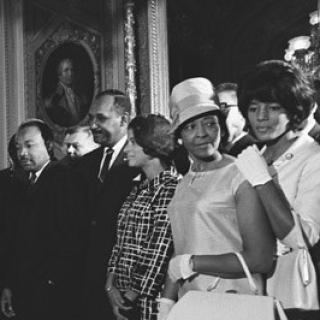 President Lyndon B. Johnson signs the Voting Rights Act while a crowd looks on. Source: Wikimedia