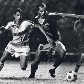 Two soccer players run after ball in rain. [Reprinted with permission of the DC Public Library, Star Collection, © Washington Post]