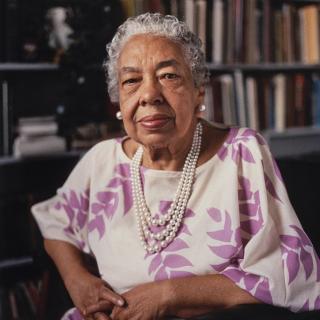 Journalist Alice Dunnigan poses with bookshelves behind her much later in her life.