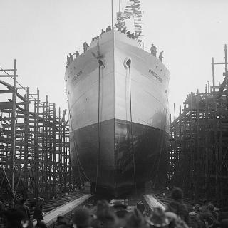 Back of peoples' heads in the foreground with a large boat in the background. 