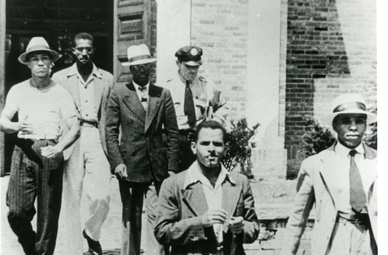 Police officer escorts five young African American men out of the Alexandria, VA Library on August 21, 1939.