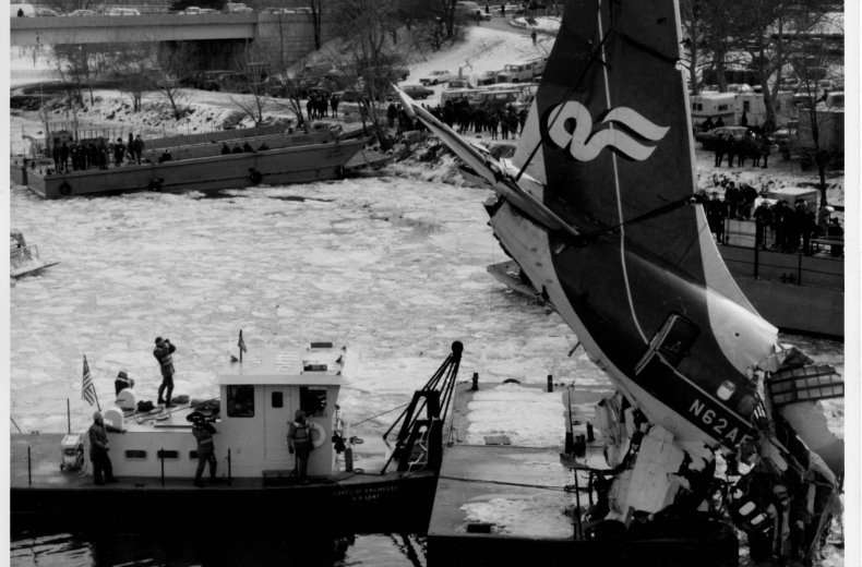 Tail section of wrecked Air Florida plane is lifted above boats on icy river.