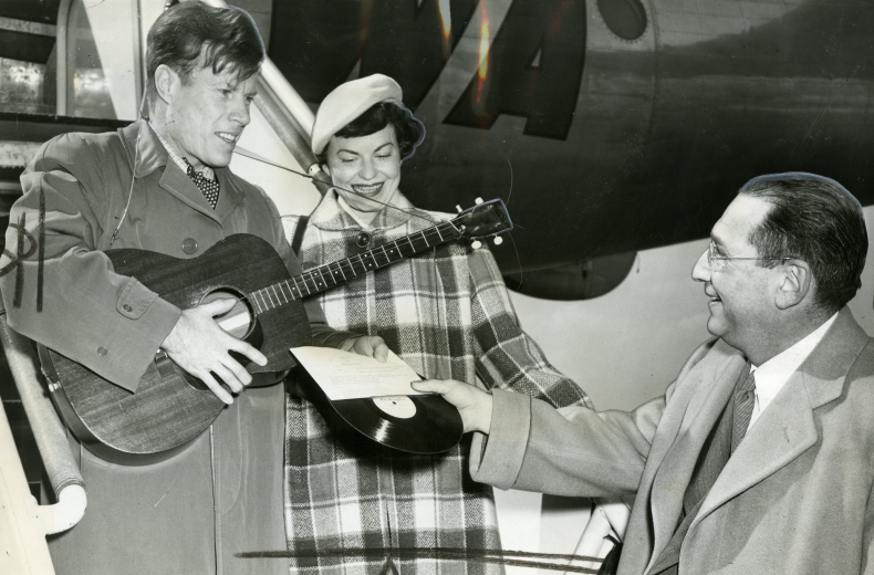 From left to right, Jimmie Dodd and his wife, Ruth, are presented with a record of "Washington" by James H. Simon.