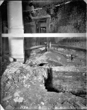 A great hole in the floor of the lower floor of the Senate small rotunda. Brick walls in the basement floor are visible.