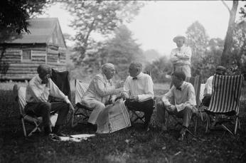 Henry Ford, Thomas Edison,Warren Harding and Harvey Firestone seated in chairs at the campsite