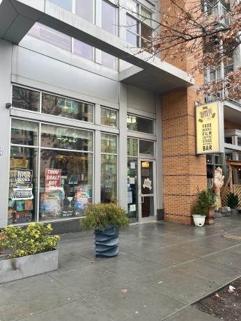 The exterior of Busboys and Poets at 14th and U Street NW, a modern corner building with large glass windows lined with posters, planters out front.