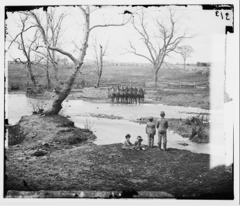 Black and white photo of Union soldiers standing before creek.