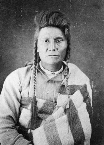 Black and white portrait photo of 37-year-old Chief Joseph dressed in striped blanket.