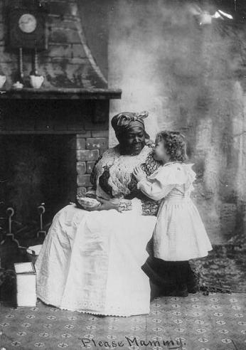 Picture of a seated black "mammy" listening to a small white girl. Source: Library of Congress