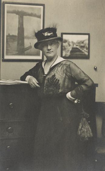 Portrait of Mattie Hewitt leaning against a dresser in a bedroom. 