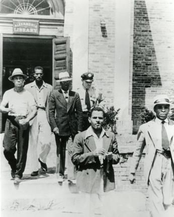 Police officer escorts five young African American men out of the Alexandria, VA Library on August 21, 1939.