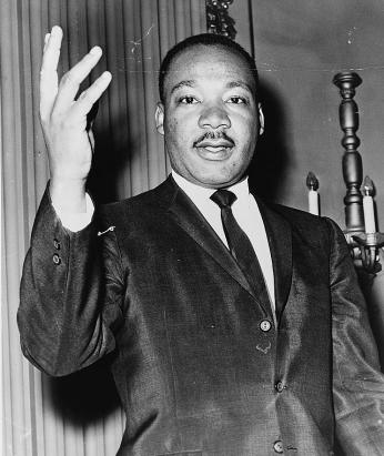 Dr. Martin Luther King, Jr. dressed in a suit and raising right hand. (Source: Library of Congress)