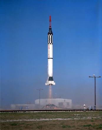 Color photo of NASA rocket lifting off from launch pad on with clear blue skies.