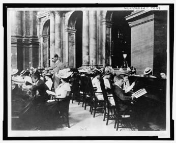 “Students in the Reading Room of the Library of Congress with the Librarian of Congress, Herbert Putnam, watching” (Photo Source: Library of Congress) Johnston, Frances Benjamin, photographer. Students in the Reading Room of the Library of Congress with the Librarian of Congress, Herbert Putnam, watching. Washington D.C, 1899. [?] Photograph. https://www.loc.gov/item/98502945/.