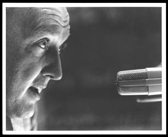 An up close shot of Grant talking into a microphone (1960).