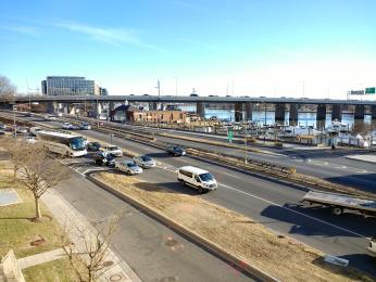 A modern picture of Maine Ave. Southwest. The street cuts through the center of the image. The Potomac can be seen running parallel to the road. The beginning of the Wharf is in the left background. 