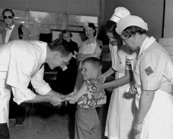 Dr. Richard Mulvaney administers the trial Polio vaccine to Randall Kerr with two nurses looking on