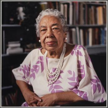 Journalist Alice Dunnigan poses with bookshelves behind her much later in her life.