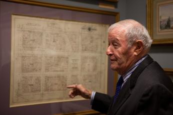 A close of photo of Mr. Small in a gallery at the GW Museum. He points to a piece on the wall and appears to be in a deep conversation regarding the piece and collection as a whole.