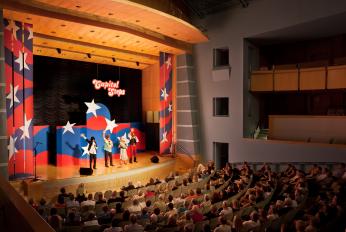 Stage with performers in the background and a seated audience in the foreground