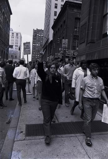 Protestors march in support of the Catonsville Nine during the trial. The photo focuses on a young woman who leads the march. (William Morgenstern, [War and draft protest], 1968. Gelatin silver print. University Archives, University of Maryland, Baltimore County, UARC Photos-09-01-0030.)