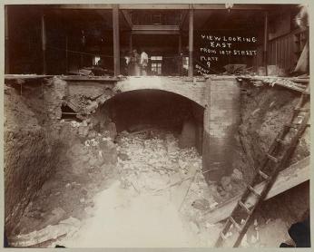 Interior of Ford's Theatre, June 10, 1893 A black-and-white photo of the interior of Fords Theatre in 1893 looking from the basement up to the first floor. There is a pile of debris in the basement. There is a small group of people standing on the first floor. Handwritten on the photo is "view looking east from 10th street."