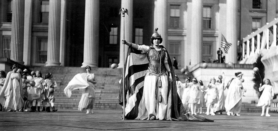 German actress Hedwig Reicher wearing costume of "Columbia" with other suffrage pageant participants standing in background in front of the Treasury Building, March 3, 1913, Washington, D.C. (Source: Library of Congress)