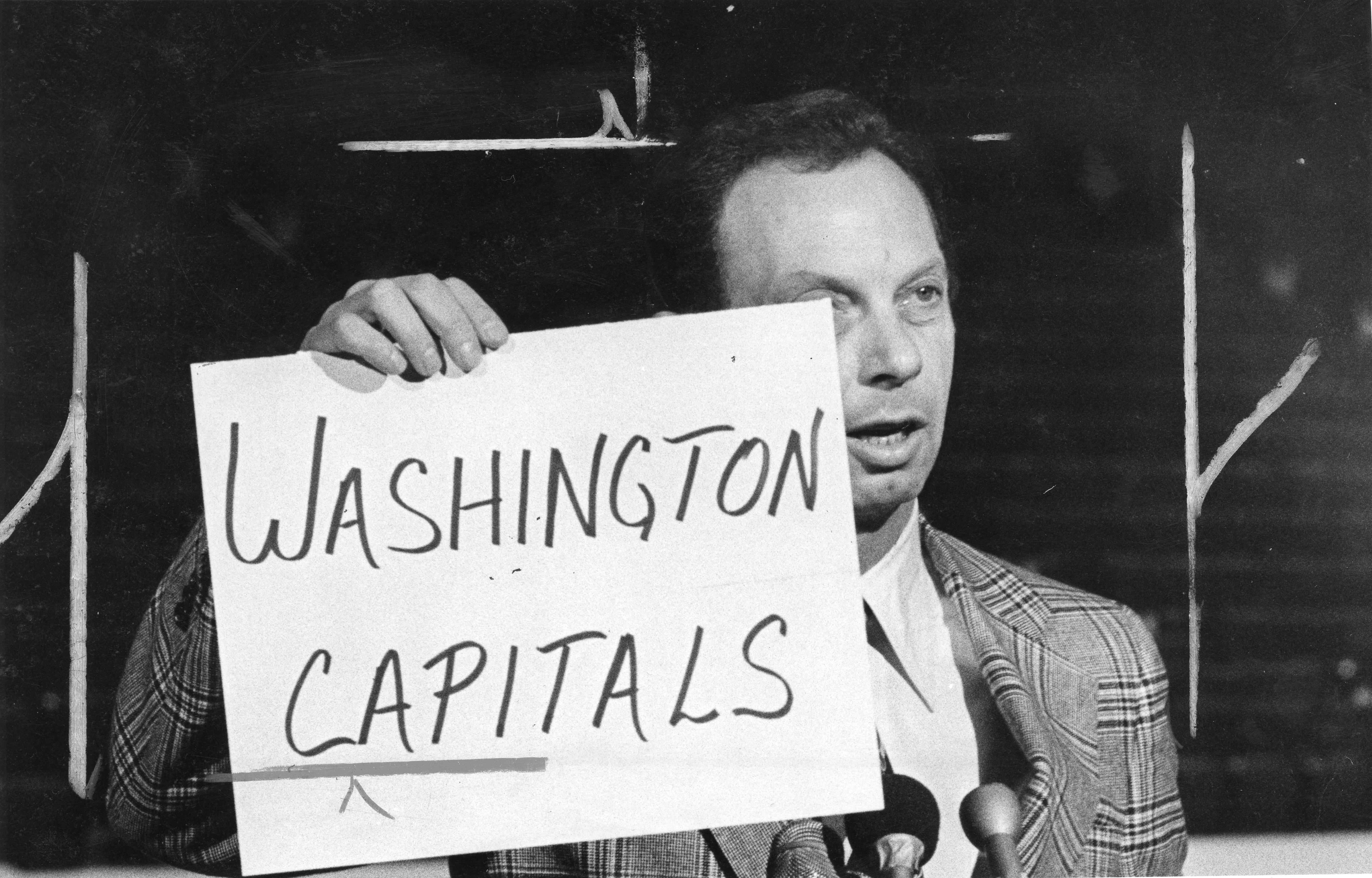 Man holds paper with "Washington Capitals" written on it.