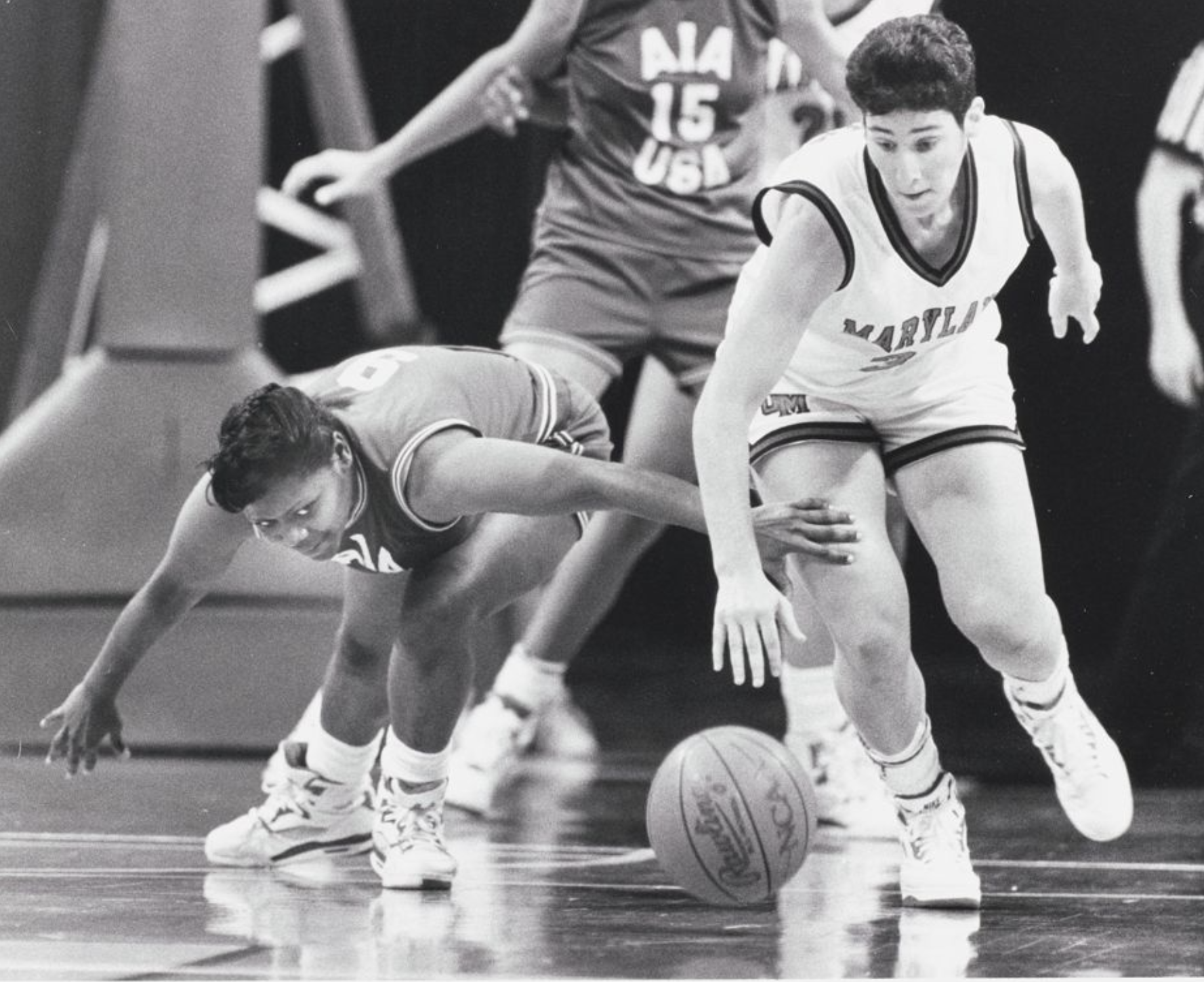 A member of the UMD women's basketball team lunges for the ball against an opponent.