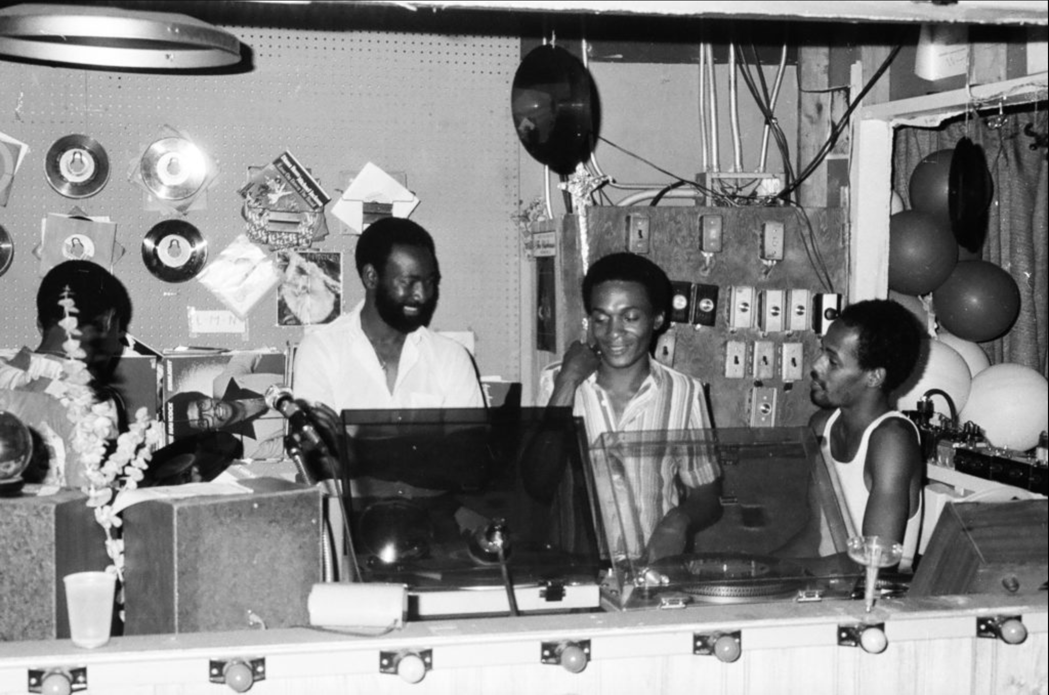 Aundrea Scott (left) behind the ClubHouse's DJ booth with an unidentified DJ and other club staff members. 