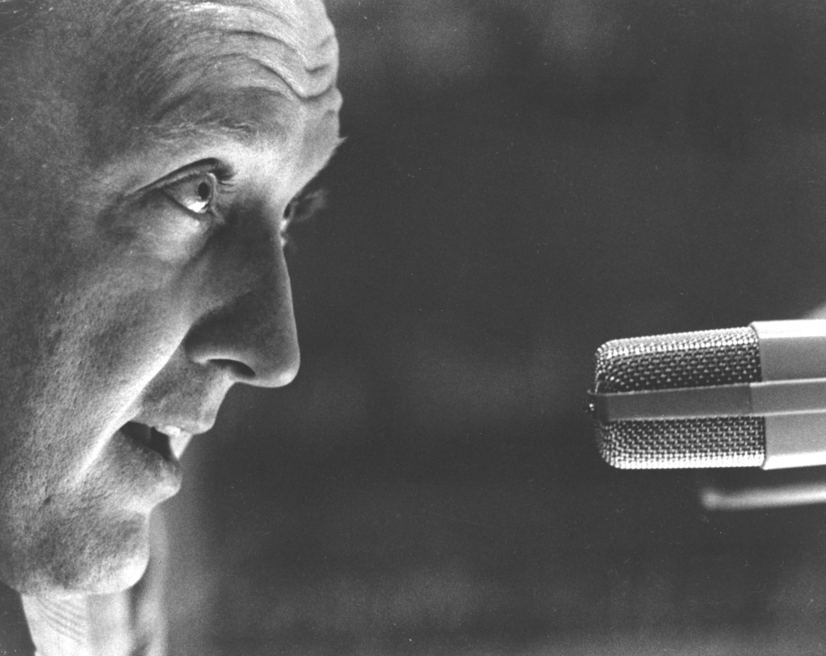 An up close shot of Grant talking into a microphone (1960).