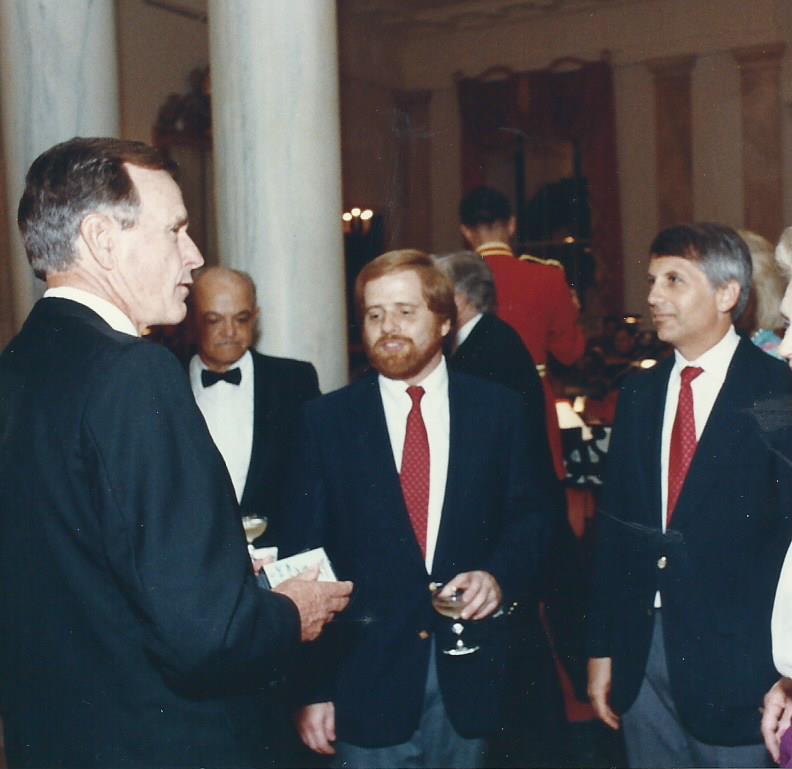 Jim Aidala and Bill Strauss standing with President George H.W. Bush in the White House.