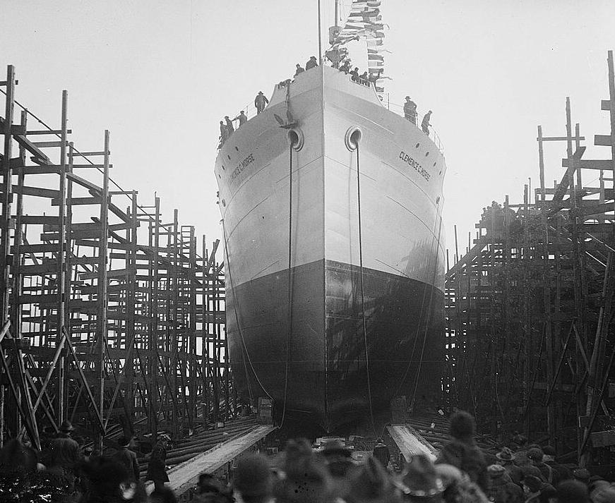 Back of peoples' heads in the foreground with a large boat in the background. 