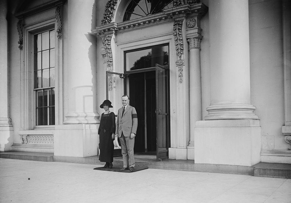 Calvin and Grace Coolidge stand outside the entrance to the White House