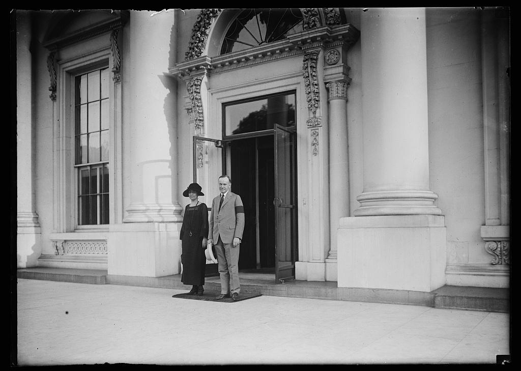 Calvin and Grace Coolidge stand outside the entrance to the White House